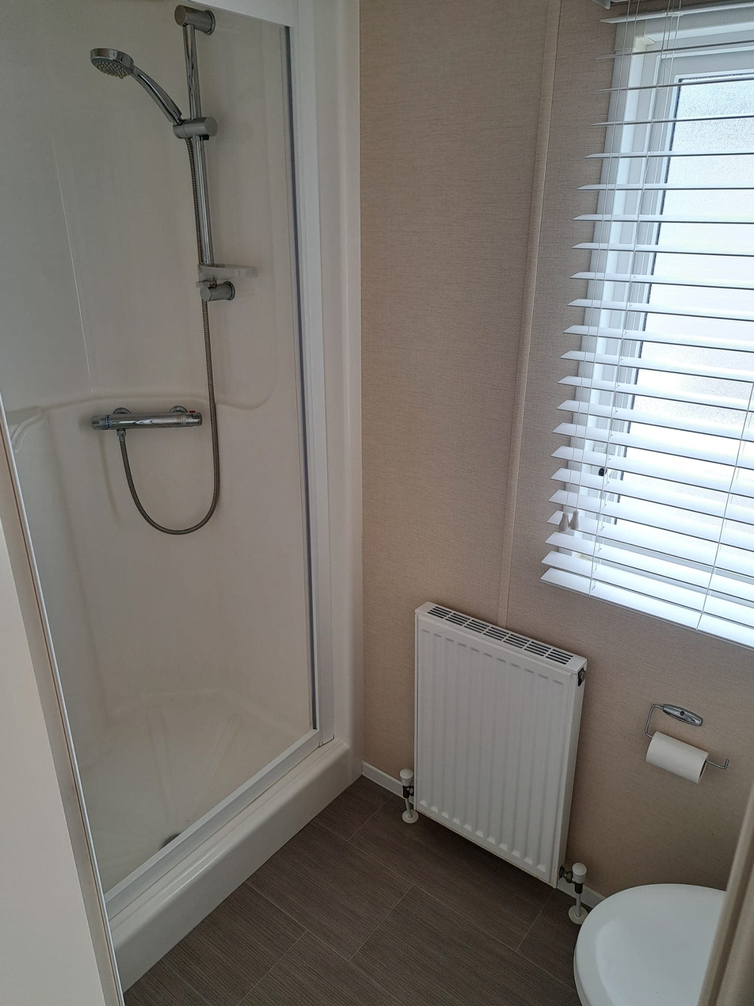 Shower room with mains-pressure thermostatic shower and a radiator