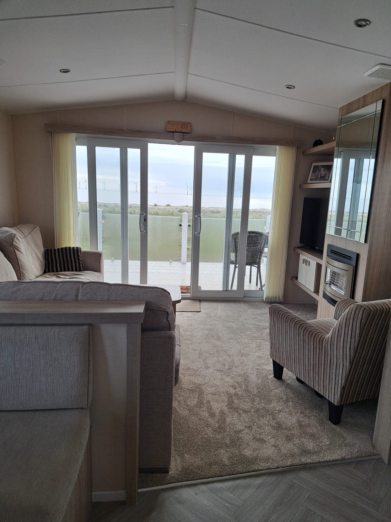 Lounge with sliding doors open onto the decking, dunes and sea beyond